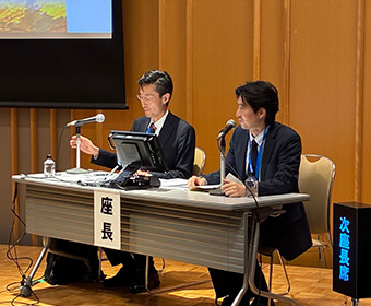 技術-1 座長の長束氏とコメンテータの根岸氏